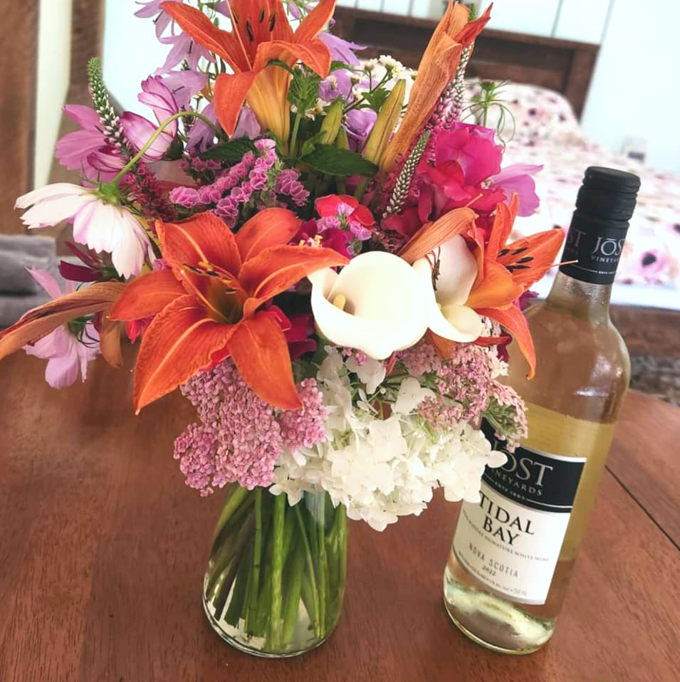Bouquet of flowers and bottle of Nova Scotia wine for a romantic glamping stay